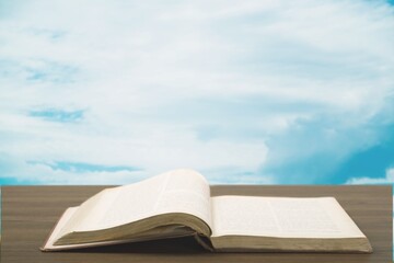 Wall Mural - Holy Bible book on a wooden desk and sky background