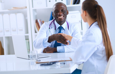 Two happy smiling young medical people handshaking at office