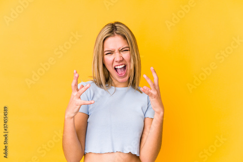 Young blonde caucasian woman isolated on yellow background screaming with rage Tableau sur Toile