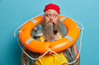 © wayhome.studio  - Thoughtful mariner carries inflated ring buoy on neck, ready to rescue people at sea, has thick long beard, smokes pipe, contemplates about something. Seafarer with safety equipment stands indoor