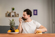 © Ivan - A young man sits at a table and talks about the usefulness of fruits, he picks them up and shows avocado. Healthy food