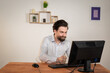 © Ivan - Angry office worker, angry man with a beard sits at a table with computer, looks at monitor, hit the keyboard with hand