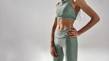 Perfect Shape. Cropped Shot Of Slim Fitness Model In Sportswear Posing Isolated Over Grey Background