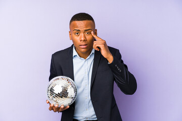 Wall Mural - Young latin man holding a ball party isolated showing a disappointment gesture with forefinger.