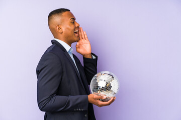 Wall Mural - Young latin man holding a ball party isolated shouting and holding palm near opened mouth.