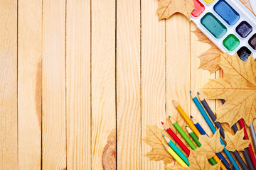 Wall Mural - back to school concept. education and study stationery on a wooden desk. above view. decorated with yellow maple leaves