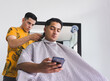 © Habitante Stock - client uses his cell phone while getting a haircut at a barbershop