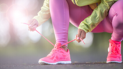 Wall Mural - Woman runner tying shoelaces before jogging in autumn tree alley park