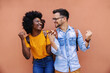 © Dusan Petkovic - Young cute overjoyed multicultural couple holding hands and fists while standing on the street.
