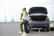 © alexkich - Replacing the wheel of a car on the road. A man doing tire work on the sidelines.