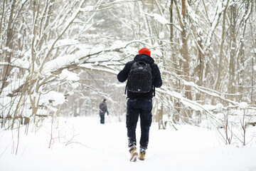 A man in the winter in the forest. A tourist with a backpack goes through the woods in winter. Winter ascent.