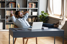 Smiling Peaceful African American Man Resting, Leaning Back In Office Chair, Sitting With Hands On Desk With Laptop, Calm Lazy Young Businessman Student Relaxing After Work Done At Workplace
