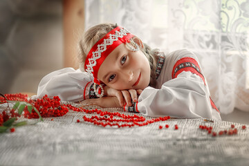 Wall Mural - A beautiful Russian girl in a folk costume lay down on the table. Portrait of a girl in a traditional costume. Russian tradition.