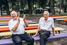 Two Old Senior Adult Men Have A Conversation Outdoors In The City Park.