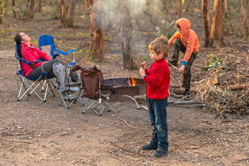 Kids burning fire at Kuitpo forest camping ground while their mother relaxing in the chair during school holidays