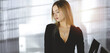 © rogerphoto - Successful young businesswoman is standing straight in a sunny cabinet of a firm. Business headshot or portrait of a secretary in an office