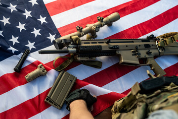 Wall Mural - Close-up of unrecognizable soldier standing at re-assembled rifle on American flag