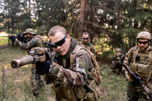 Fotografía Focused armed soldiers in uniform carrying rifles and examining forest terrain