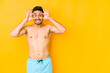 © Asier - Young caucasian man with swimsuit isolated on yellow background Young caucasian man with trkeeping eyes opened to find a success opportunity.