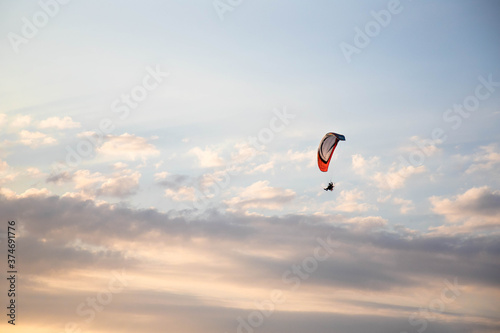 Parapente volant dans la lumière du soir sur un fond de nuages éclairés par les Tableau sur Toile