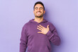 © Asier - Young caucasian man isolated on purple background laughs out loudly keeping hand on chest.