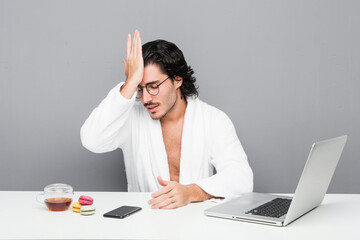 Wall Mural - Young handsome man working after a shower forgetting something, slapping forehead with palm and closing eyes.