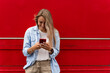 © Dulin - Young hipster girl using mobile phone against red background