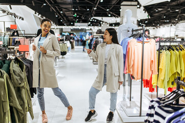 Canvas Print - Two girls trying on coats in clothing store