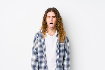 Wall Mural - Young long hair man posing isolated funny and friendly sticking out tongue.