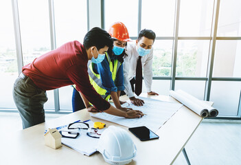 Wall Mural - Construction team with business man engineer and architect is discussing on working table while wearing protective mask for virus protection