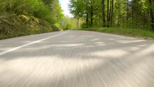 POV, LENS FLARE: Speeding Down An Empty Asphalt Road Winding Through A Lush Forest On A Sunny Spring Day. Carefree Joyride Through The Idyllic Green Slovenian Countryside In A Powerful Supercar.