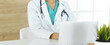 Unknown female doctor sitting and using laptop computer in clinic, close-up. Medicine concept