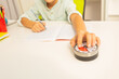 Little autistic boy hold lesson timer with hand while doing writing exercise, understanding time