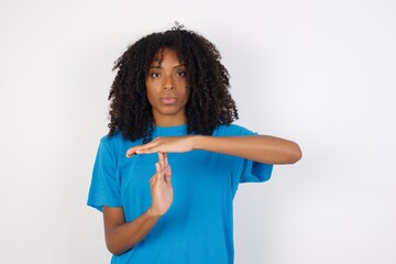 Wall Mural - Young african woman with curly hair wearing casual blue shirt over white background being upset showing a timeout gesture.