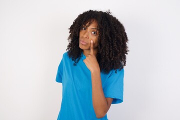 Wall Mural - Young african woman with curly hair wearing casual blue shirt over white background Pointing to the eye watching you gesture, suspicious expression.