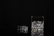 Empty glass for whiskey, cognac or bourbon next to it is scattered ice, old type of fashion, copy space, selective focus, there is a place to write text