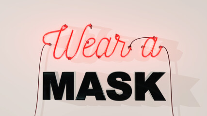 Neon sign on a white wall background saying Wear a mask warning people to put on a mask due to the 2020 coronavirus covid-19 pandemic.