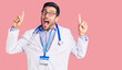 © Krakenimages.com - Young hispanic man wearing doctor uniform and stethoscope smiling amazed and surprised and pointing up with fingers and raised arms.