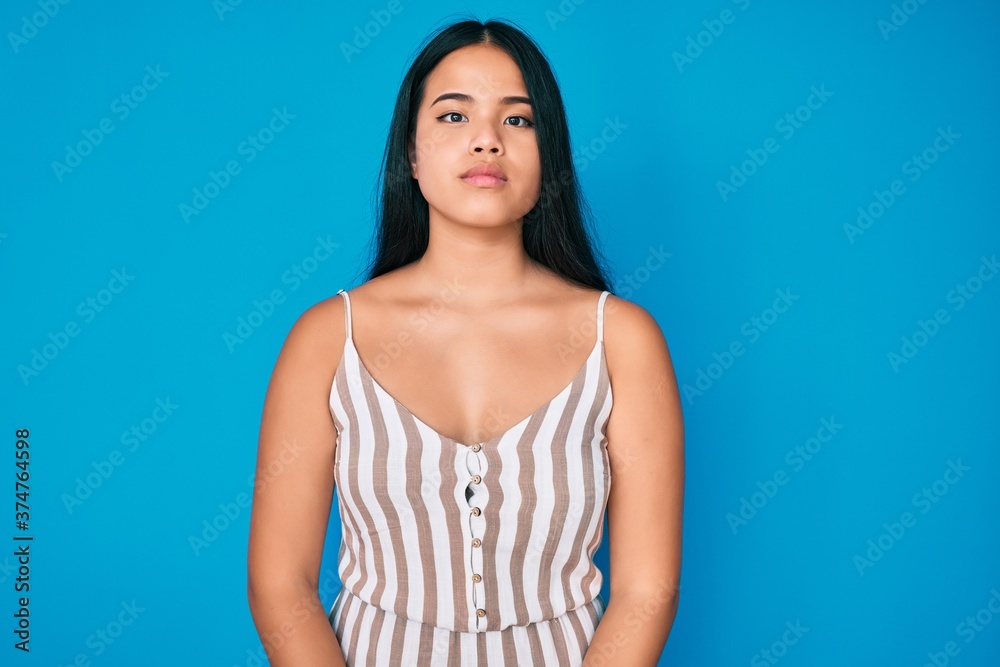 Young beautiful asian girl wearing casual clothes relaxed with serious expression on face. simple and natural looking at the camera.