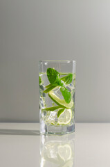 Wall Mural - Mojito cocktail with lime and mint in tall glass. Fresh mojito in glass on a gray background.