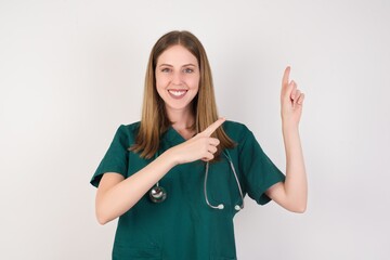 Female doctor wearing a green scrubs and stethoscope indicating with forefinger empty space showing best low prices