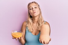 Young Blonde Girl Holding Fresh Pumpkin And Soup Looking At The Camera Blowing A Kiss Being Lovely And Sexy. Love Expression.