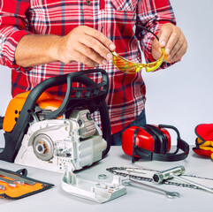 Wall Mural - Serviceman is repairing a chainsaw in repair shop. Repairman with safety equipment and chainsaw in workbench.