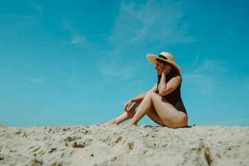 woman at sand beach in black swimsuit blue sky on background