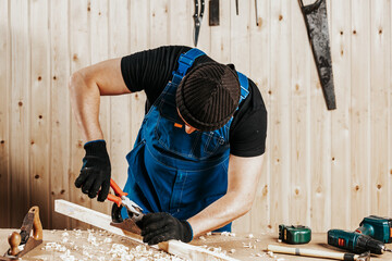 A dark-haired man adjusts with pliers plane and treating a wooden bar, work with wooden