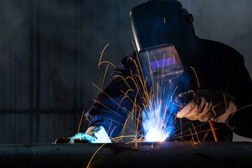 Asian workers wearing safety first uniforms and Welded Iron Mask at Steel welding plants, industrial safety first concept.