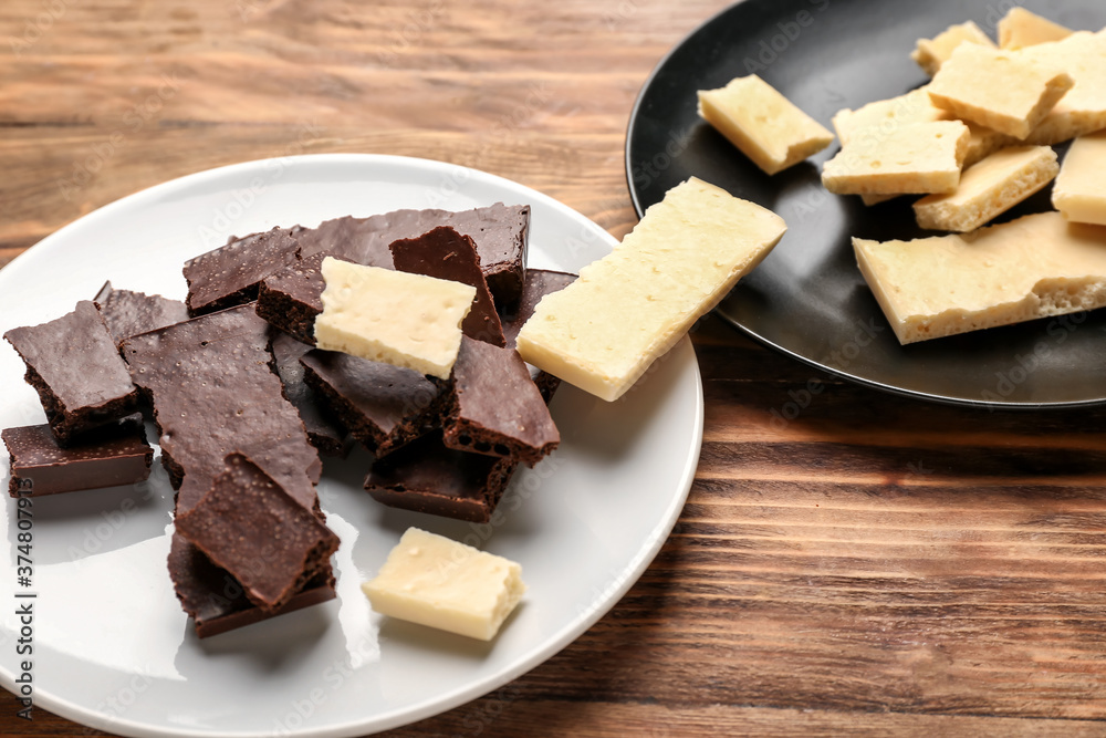Plates with different chocolate on wooden background. Racism concept