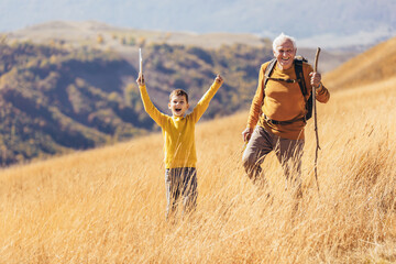 Wall Mural - Senior man with grandson on country walk in autumn.