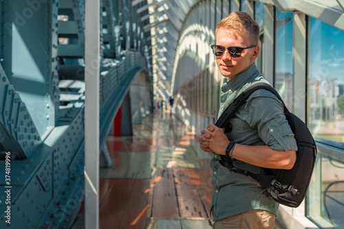 Cuadros en Lienzo A young man in sunglasses and a shirt walks along a modern glass business corrid