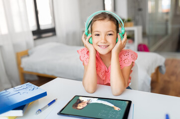 Wall Mural - education, e-learning and school concept - happy student girl in headphones with teacher on tablet computer having online lesson at home desk